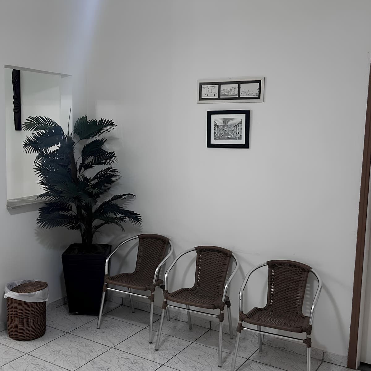 Recepção - três cadeiras em palha trançada marrom escuro, planta decorativa e quadros na parede