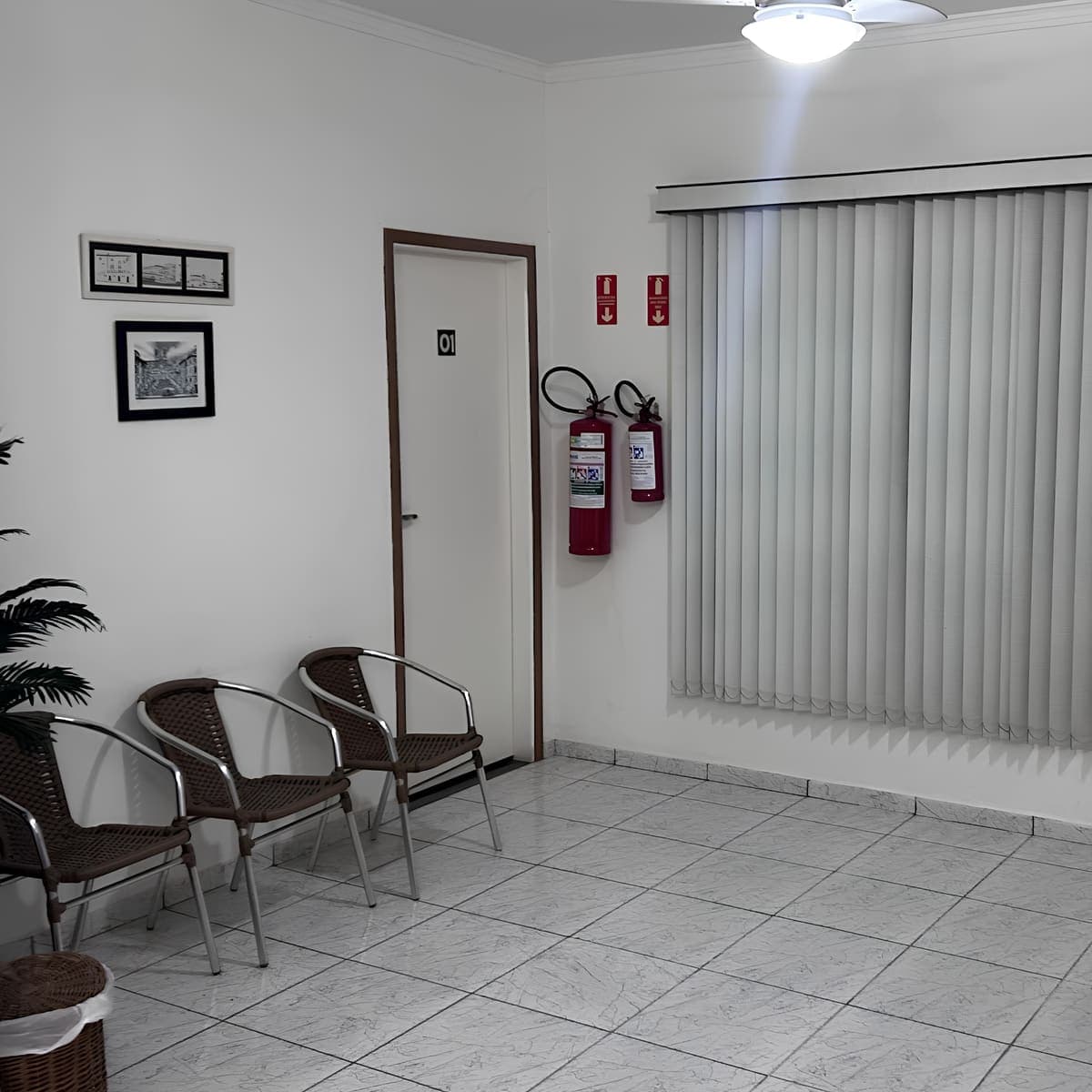 Recepção - espaço estar com poltronas e estante em madeira escura